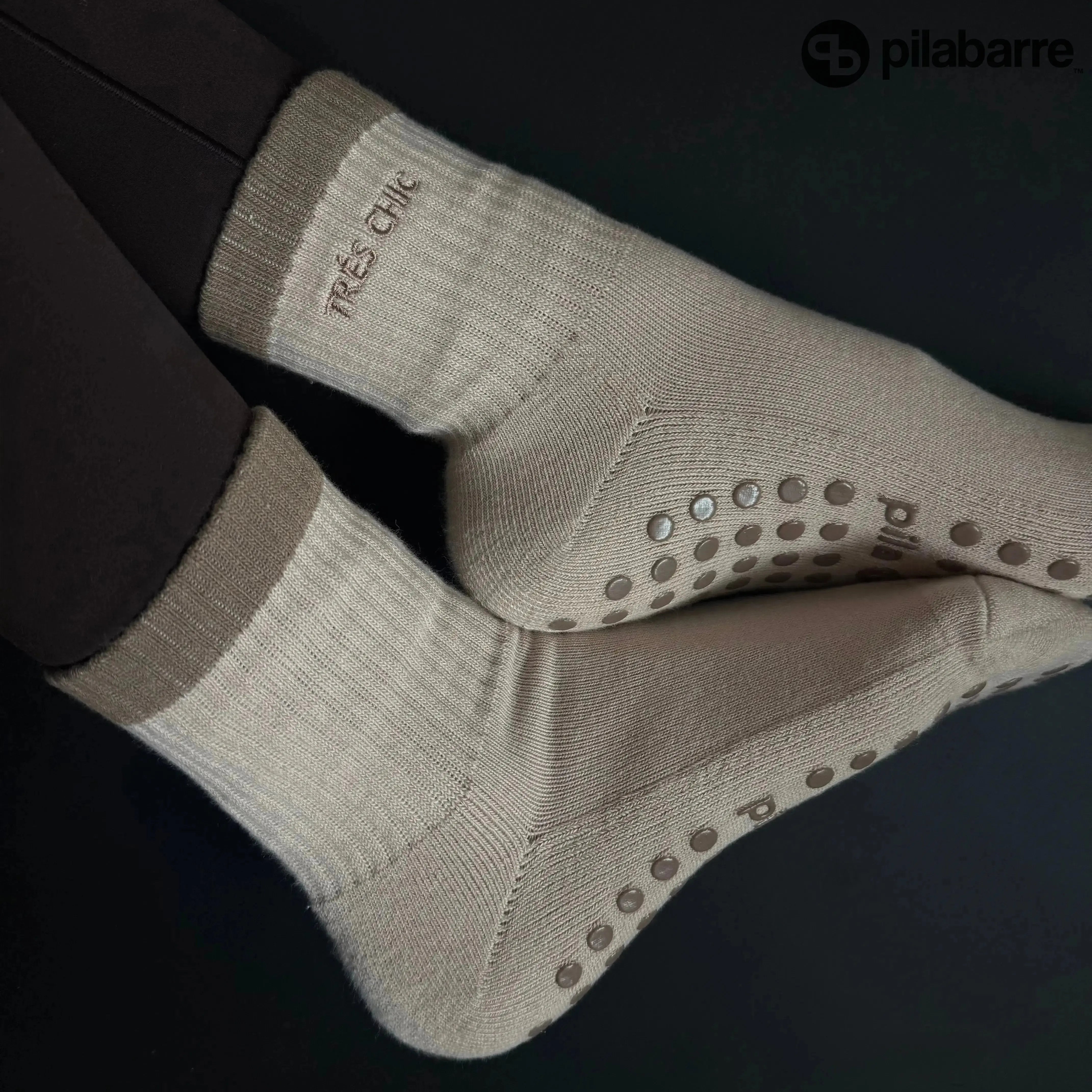 Pair of beige socks with non-slip dots on a black background