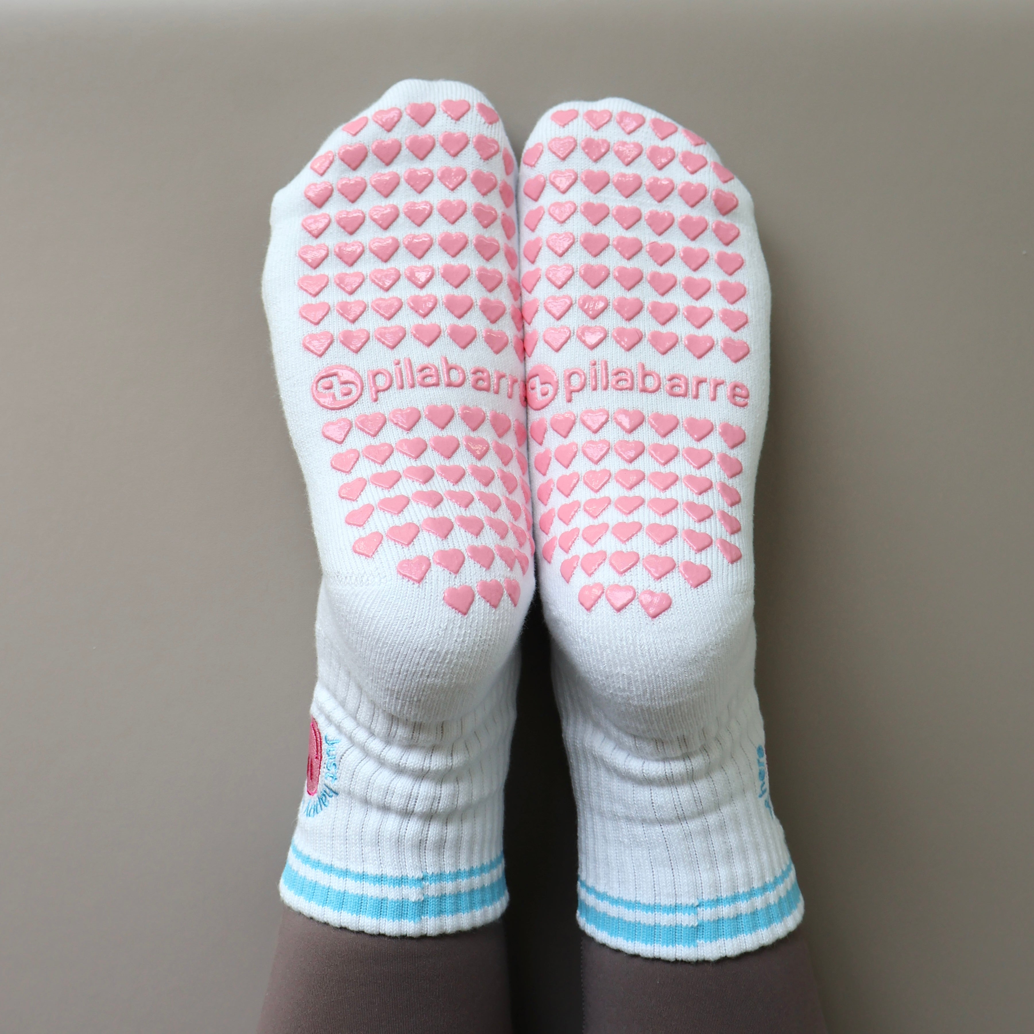 White socks with pink heart patterns and 'pilabarre' branding on a neutral background - Just Happy to be here grips