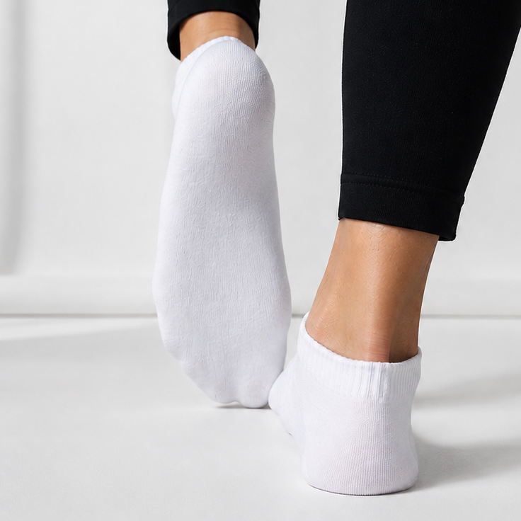 White ankle socks worn with black leggings on a light gray background