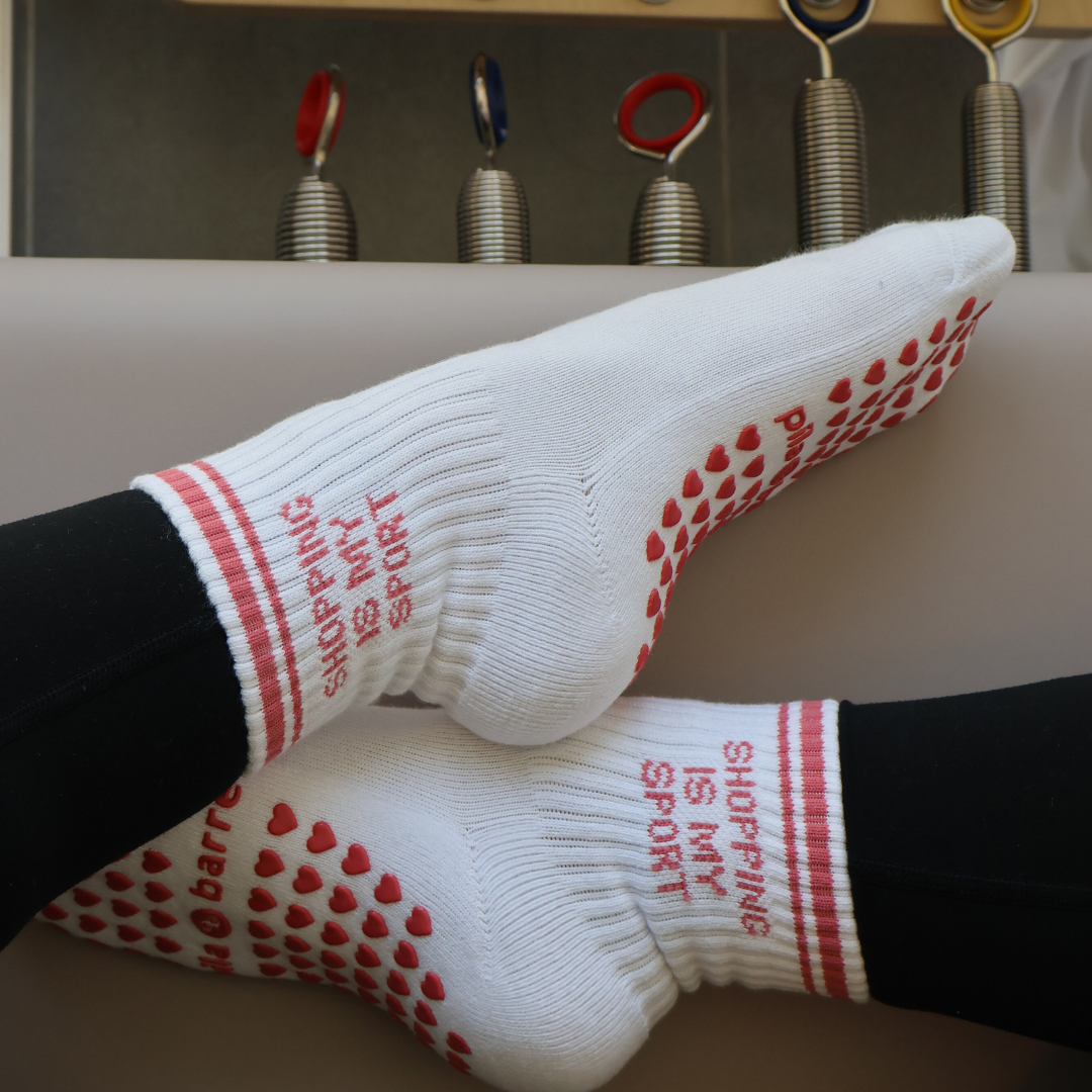 White socks with PINK SHOPPING IS MY SPORT text and patterns on a neutral background