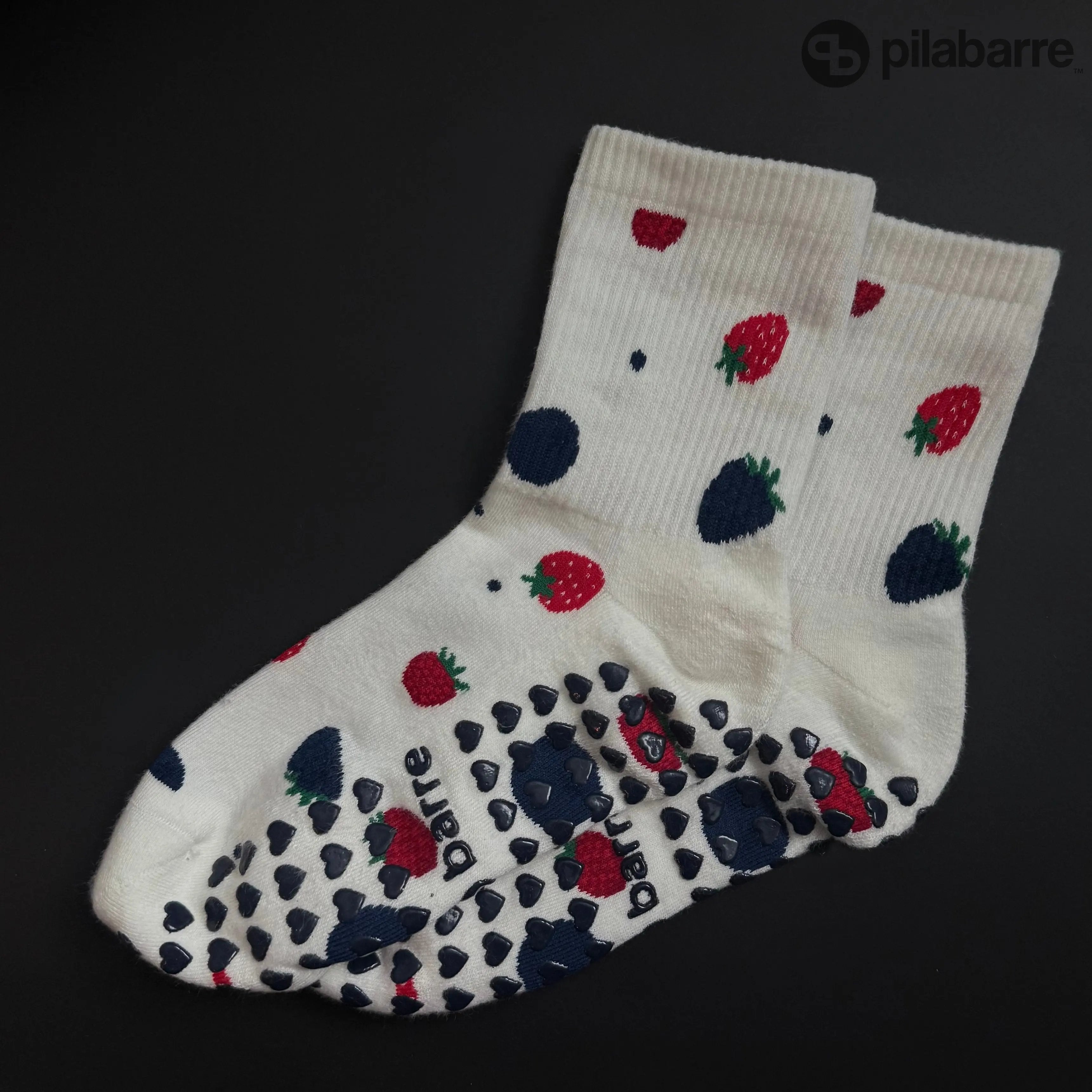 Cream Grip socks with strawberry pattern on a black background
