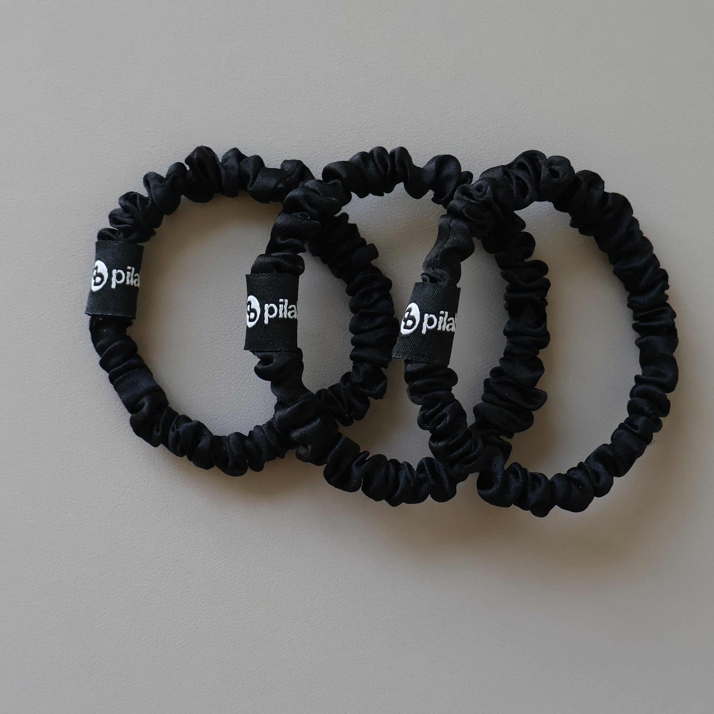 Three silk black hair ties on a white surface
